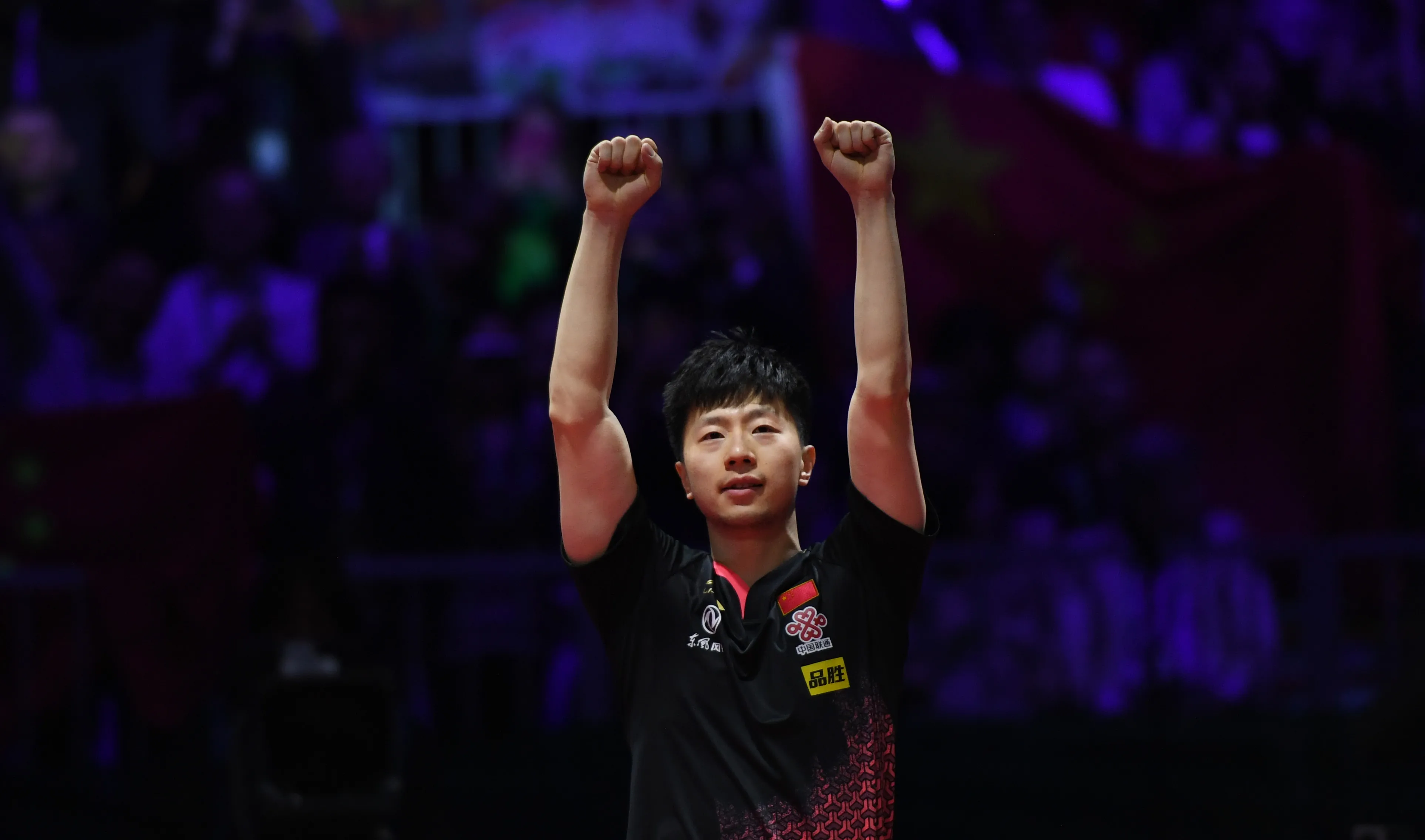 Ma Long raising both arms to the crowd after winning the championship