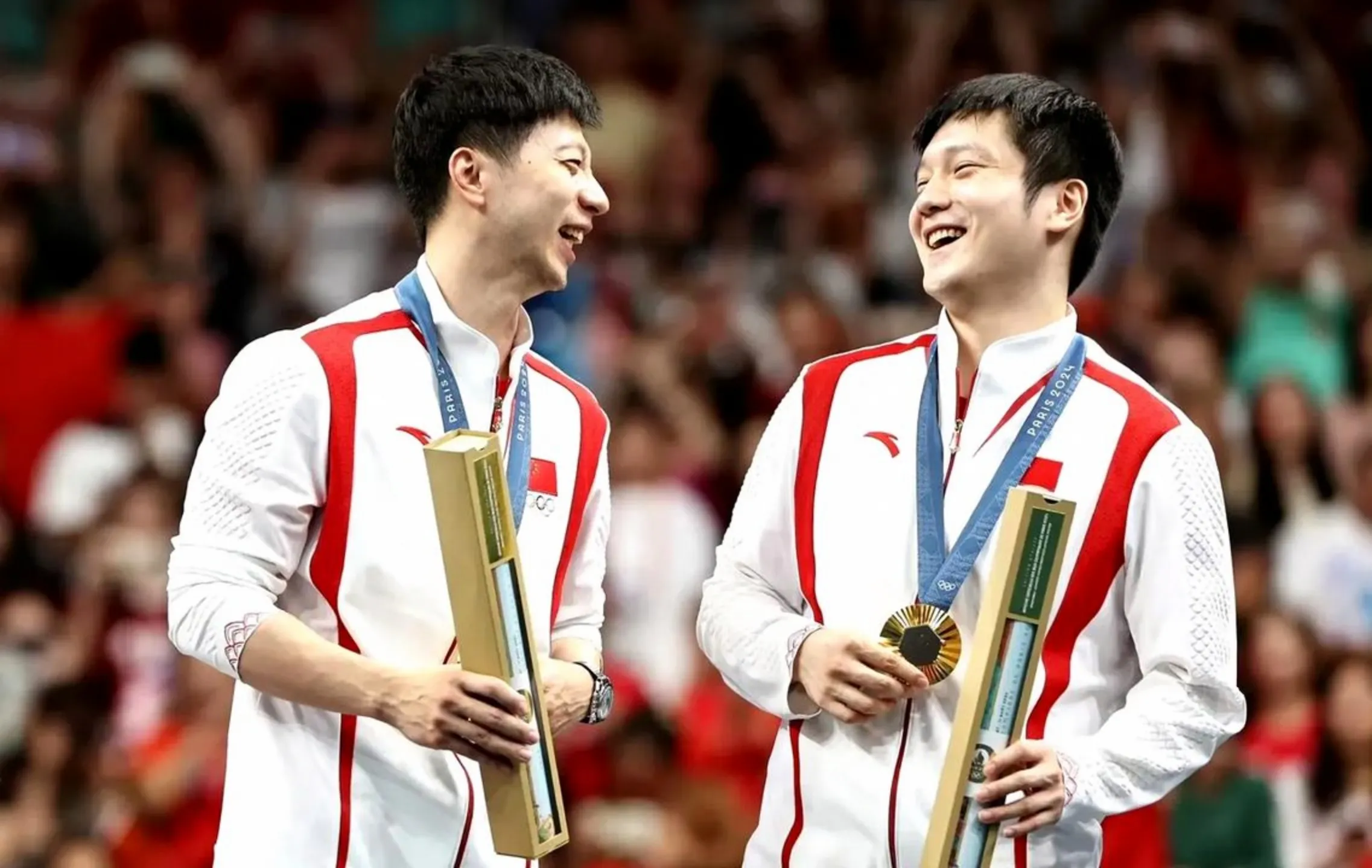 Ma Long and Fan Zhendong laughing together on the podium after a final