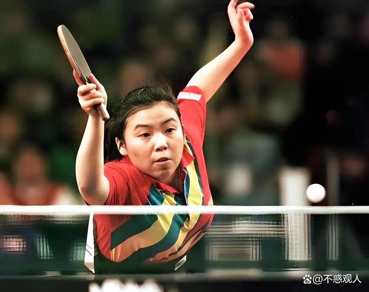 Deng Yaping crouching to return a shot during a competitive table tennis match