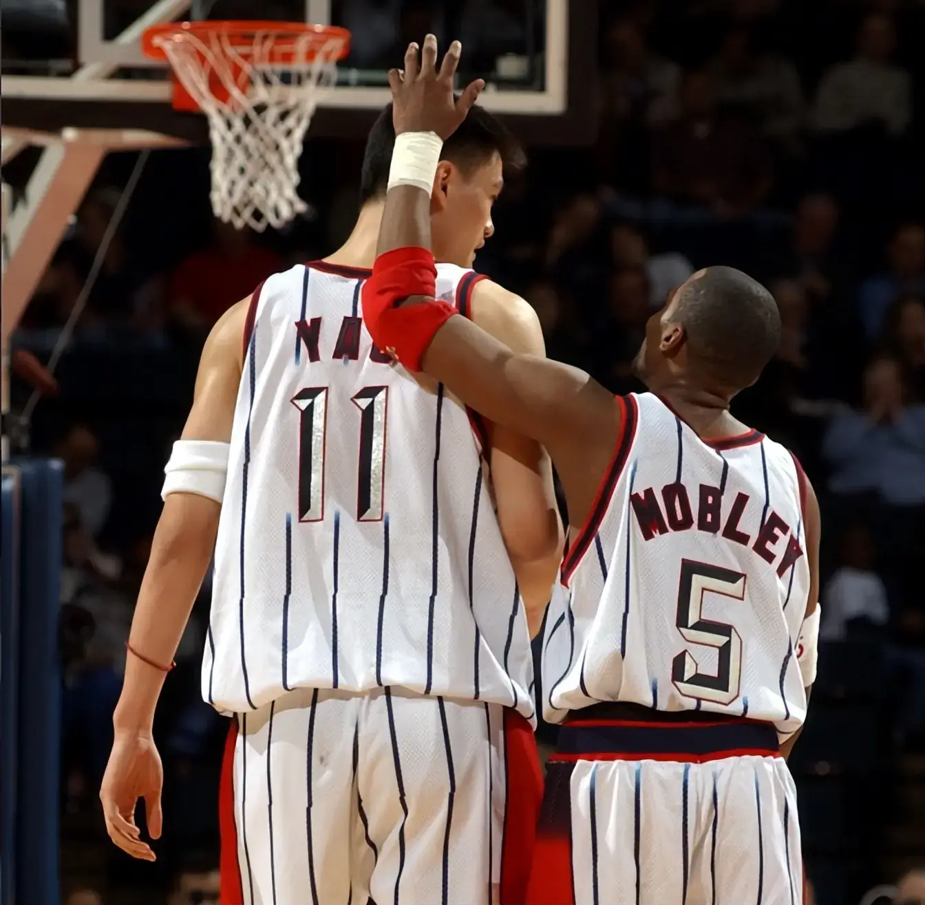 Yao Ming, wearing Houston's number 11, seen from behind with teammate Cuttino Mobley's arm around his shoulder