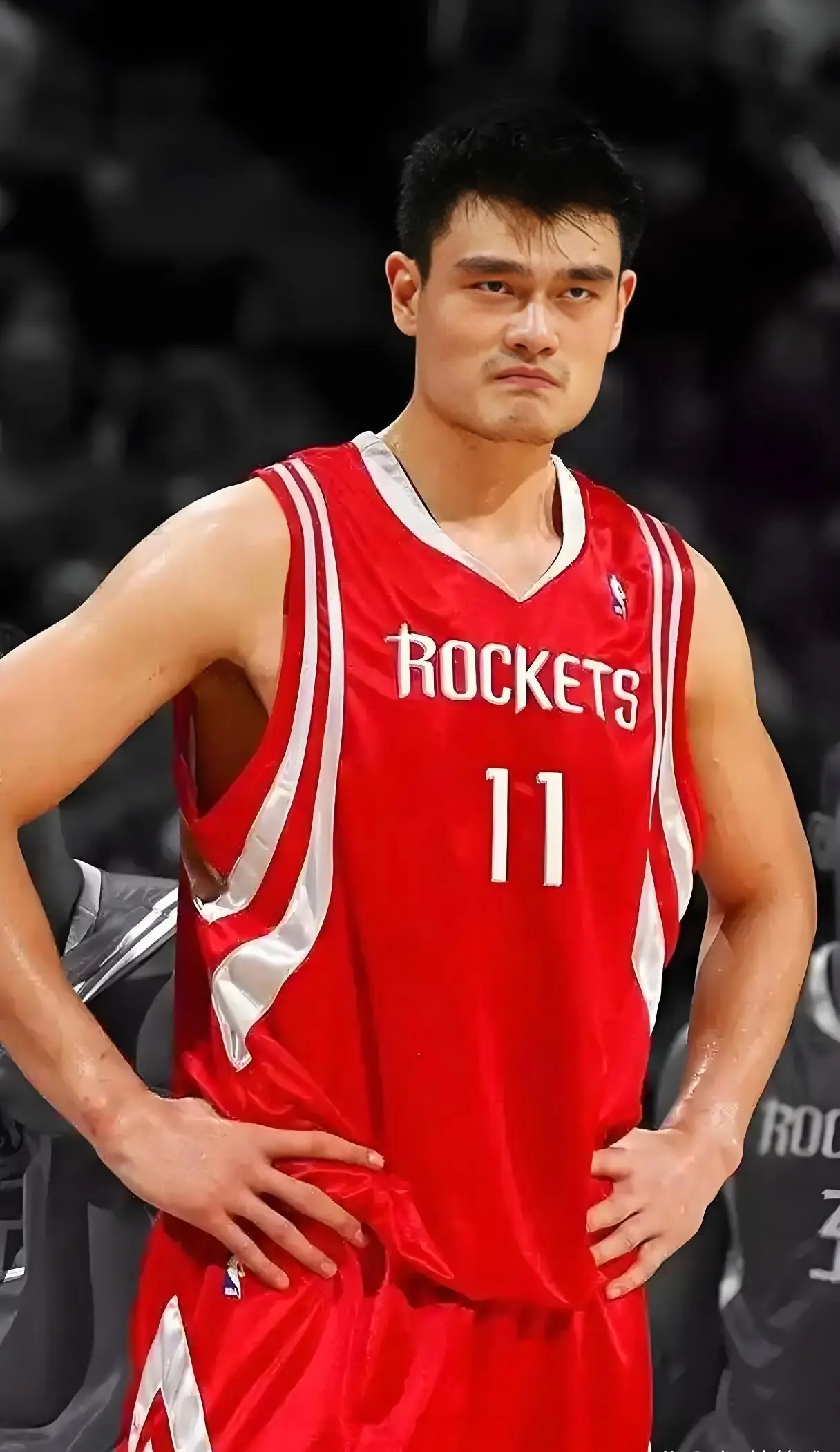Yao Ming in the Houston Rockets' red number 11 jersey, hands on hips, looking straight ahead