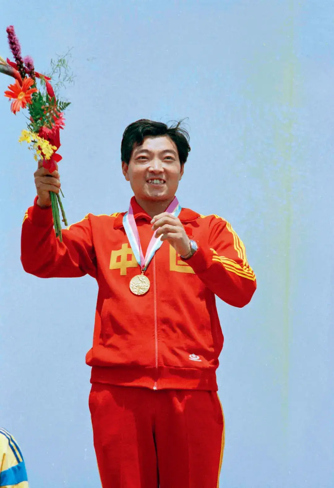 Xu Haifeng on the podium holding a bouquet after winning gold